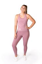 Load image into Gallery viewer, Front facing smiling woman, wearing full length pink activewear leggings with pockets with a matching pink top with a logo and the words Strong Girls Co. on the bottom right side, and white training shoes
