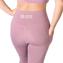 Load image into Gallery viewer, Back facing woman wearing pink activewear leggings with pockets with a logo on the back middle waistband with the words Strong Girls Co., and a matching pink top 
