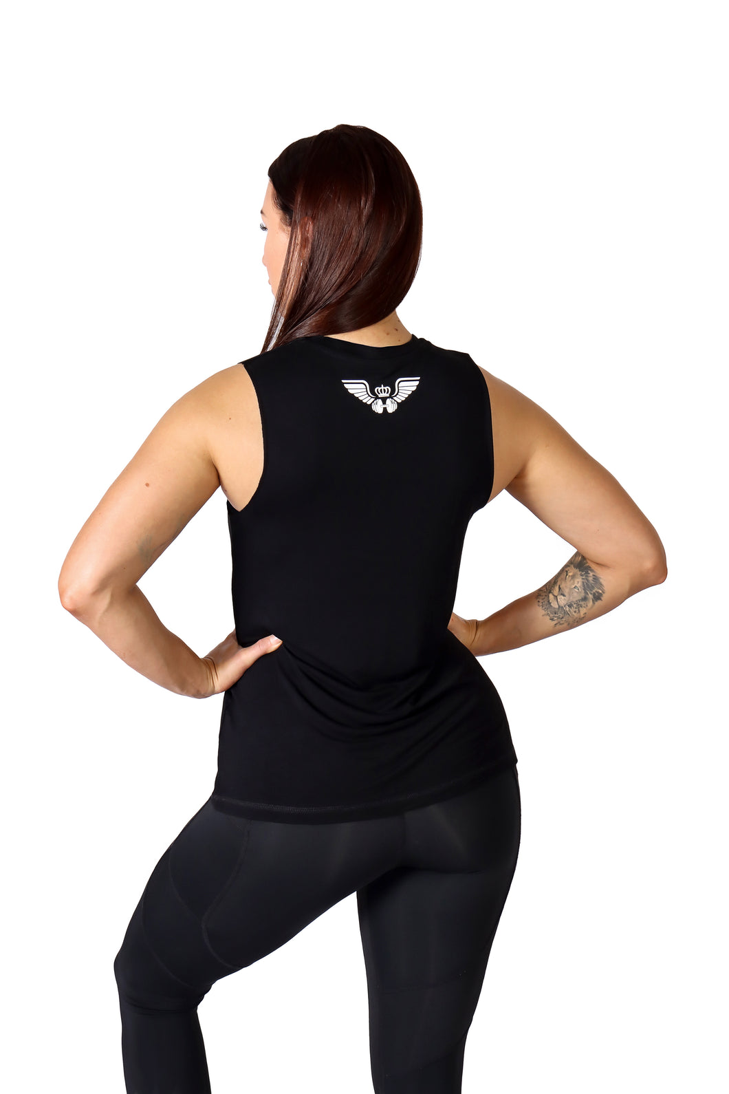 Back facing  woman with both hands on hips wearing black activewear leggings with pockets and a black shirt with an image of a weight lifting dumbbell with wings and a crown in the upper middle back.