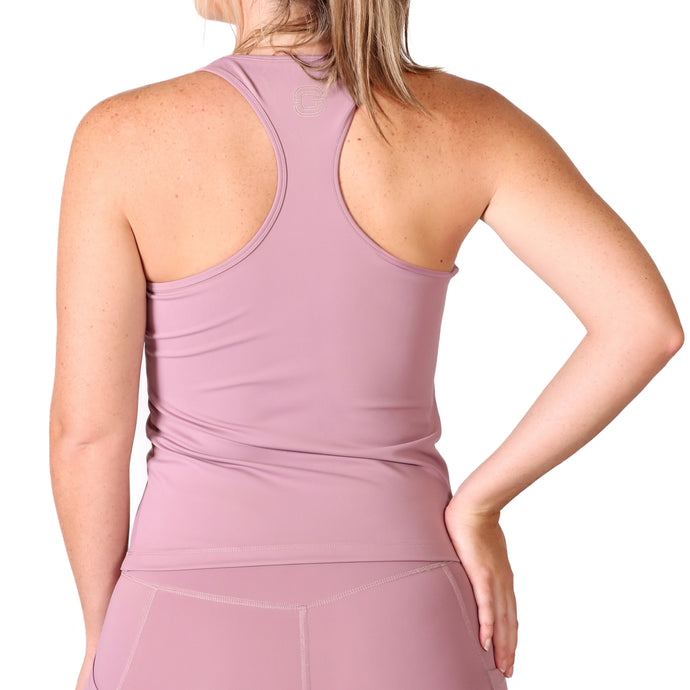 Back of a woman wearing pink activewear leggings and a pink racer back style top with a small white logo in the upper middle back.