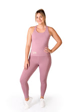 Load image into Gallery viewer, Front facing smiling woman, wearing full length pink activewear leggings with pockets with a matching pink top with a logo and the words Strong Girls Co. on the bottom right side, and white training shoes
