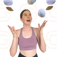 Load image into Gallery viewer, Woman smiling wearing a pink crop top and throwing bra pads in the air like confetti.
